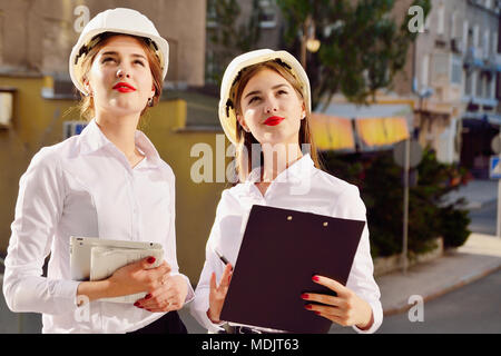 Mädchen in Gebäude weiße Helme mit Tabletten in die Hand. Frauen sind Ingenieure. Weibliche Berufe. Stockfoto
