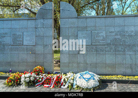 Warschau, Polen - 19. April 2018: Kerze, Rosen und gelbe Narzissen am Umschlagplatz. Stockfoto