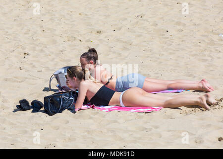 Bournemouth, Dorset, Großbritannien. April 2018 20. UK Wetter: Strände sind als Besucher strömen zum Strand die heißen, sonnigen Wetter Bournemouth zu genießen voll. Zwei junge Frauen, Sonnenbaden am Strand. Credit: Carolyn Jenkins/Alamy leben Nachrichten Stockfoto