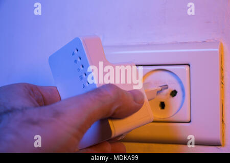 Man WLAN Repeater einsetzen in die Steckdose an der Wand. Das Gerät helfen, drahtloses Netzwerk zu Hause oder im Büro. Stockfoto