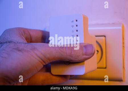 Man WLAN Repeater einsetzen in die Steckdose an der Wand. Das Gerät helfen, drahtloses Netzwerk zu Hause oder im Büro. Stockfoto