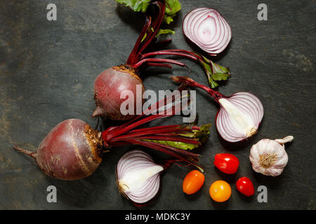 Frische ganze rote Beete mit roten Zwiebeln, Knoblauch und Tomaten auf schiefer Tisch mit Platz kopieren Stockfoto