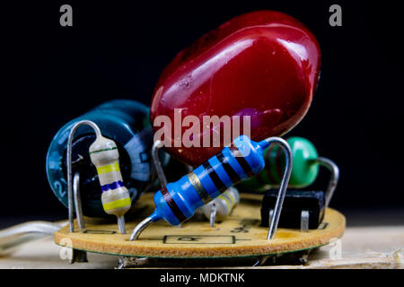 Elektronik in hoher Vergrößerung. Widerstände und Dioden verlötet auf einer Platine. Der dunkle Hintergrund. Stockfoto