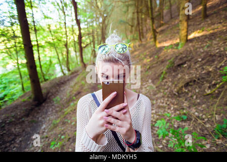 Junge Frau fotografieren mit Telefon im Wald Stockfoto