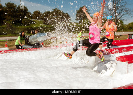 Junge Frauen mit Blasen in einem Schaum Grube springen gesprüht, da sie in das Lächerliche Hindernis Herausforderung am 5. April 2014 in Atlanta, GA. Stockfoto