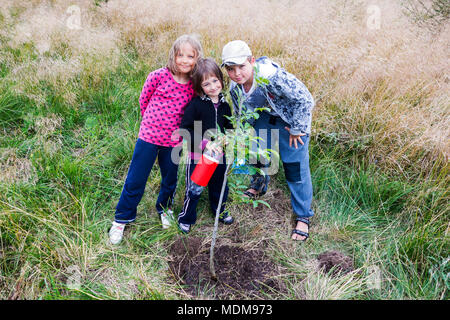 Drei Kinder Bewässerung neu gepflanzter Walnussbaum. Stockfoto