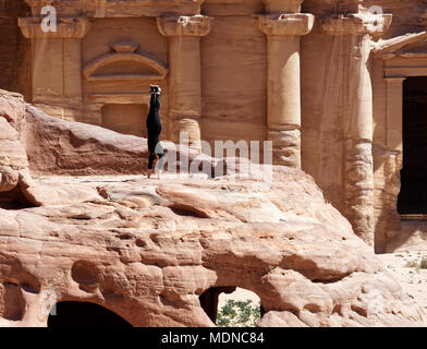 Petra, Wadi Musa, Jordanien, 9. März 2018: Ein junges Mädchen in einem schwarzen Sportanzug üben einen handstand vor al-deir Kloster in der Wüste Stockfoto