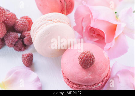 Macarons mit Himbeeren, Marshmallows auf dem Hintergrund der schönen Blumen Rosen. Nachtisch Nahaufnahme. Ein horizontaler Rahmen. Stockfoto