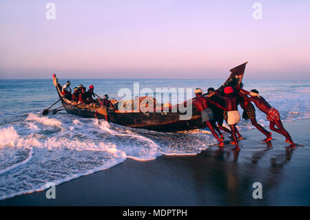 Kerala, Indien; Fischer, die ihr Boot in das Meer bei Sonnenaufgang Stockfoto