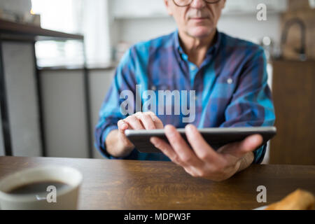 7/8-Portrait von älteren Mann hält Tablet in der Küche Stockfoto