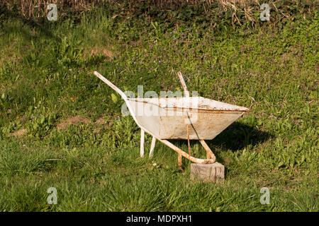 Alte vintage Schubkarre auf einem grünen Gras im Garten. Stockfoto