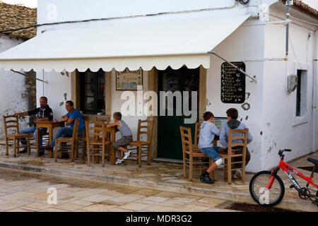 Einheimische entspannen in einer Seitenstraße Kafenion, Gaios, Paxos, Griechenland Stockfoto