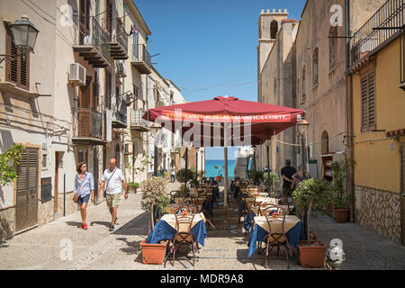Tisch und Stühle draußen ein Restaurant, L'Antica Corte, in Cefalu, Sizilien, Italien auf einem sonnigen Sommertag im August. Stockfoto