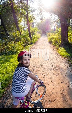 Mädchen auf dem Fahrrad im Sommer Park draußen, Sonnenuntergang. Stockfoto