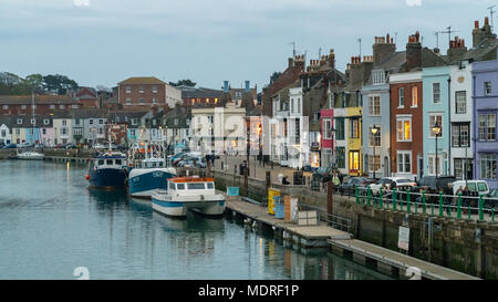 Dorchester, Dorset, England, Großbritannien - 21 April, 2017: Abendlicher Blick von der Brücke, mit Fischerbooten am Ufer und die Menschen auf den Gehsteigen Stockfoto