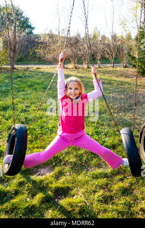 Mädchen in rosa Schwingen auf einem reifen Swing im Park. Stockfoto