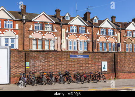 Fahrradständer mit parkenden Grenzgänger' Fahrräder am Bahnhof in Woking, Surrey, UK im Herzen der Pendler Riemen an einem sonnigen Tag mit blauen Himmel Stockfoto