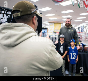 Oakland Raiders tight end Lee Smith nimmt ein Foto mit einigen Kindern bei einem Besuch des Travis Air Force Base, Calif., Exchange, Dez. 5, 2017. Smith hat sieben Spielzeiten in der NFL mit den Oakland Raiders und Buffalo Bills gespielt. Smith hat eine große Anerkennung für die Männer und Frauen dienen, denn es ermöglicht ihm zu spielen ein Spiel, das er liebt und ihn und seine Familie sicher halten. (U.S. Air Force Foto von Louis Briscese) Stockfoto