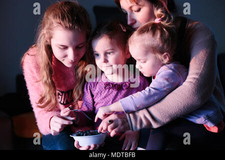 Familie, Mutter mit drei Töchtern, junges Mädchen, Kind, Kleinkind, genießen Essen frische Blaubeeren aus kleinen Schüssel zusammen zu Hause Stockfoto