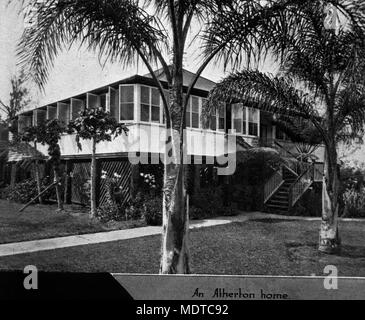 Queenslander home in einem tropischen Garten in Atherton, Queensland, eingestellt. Lage: Atherton, Queensland Beschreibung: Dieses highset Haus in Atherton hat geschlossene Veranden, näherte sich von der Vorderseite durch Treppen. Die Fenster auf der Veranda geöffnet sind, um die kühlen Brisen zu fangen. Atherton war nach John Atherton, der Pionier nomadisierende, die Rinder in den Stadtteil von Rockhampton 1877 brachte benannt. Er nahm Emerald Endstation am Ufer des Barron River. Abrechnung in Atherton begann mit der Entwicklung einer Zeder logging Camp wie vor Pocket bekannt. Atherton ist der Agricultura Stockfoto