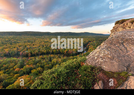 Die großen Karpfen Fluss schneidet eine Schwade durch einen farbigen Herbst Wald. Von einem Felsvorsprung auf einem Wanderweg an Porcupine Mountains Wilderness Area gesehen, Stockfoto
