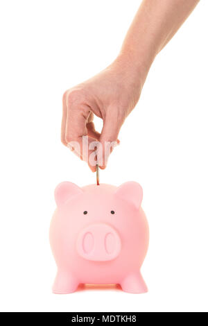 Weibliche Hand 1 Euro Münze in ein rosa Sparschwein von vorne auf einem weißen Hintergrund zu sehen setzen Stockfoto
