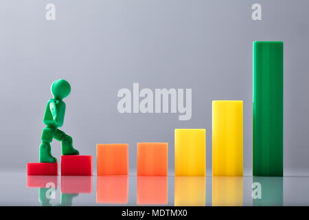 Menschliche Figur zu Fuß auf die bunten Business graph Vor grauem Hintergrund Stockfoto