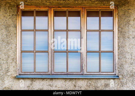 Drei Fenster mit Jalousien auf einem grauen Fassade. Stockfoto