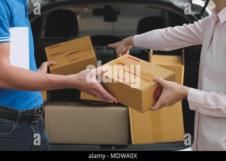 Frau erhalten Paket von Delivery Man. männliche Post Kurier Person liefern Karton Stockfoto