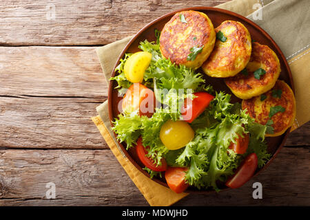 Frisch zubereitet Kartoffelpuffer mit frischem Salat in der Nähe serviert auf einem Teller. horizontal oben Ansicht von oben Stockfoto