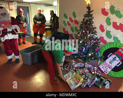 Santa Claus und seinen Kopf elf liefern Weihnachtsgeschenke für die Kinder bei Danger Bay Schule auf Kodiak Island, Alaska, Dez. 5, 2017. Coast Guard Air Station Kodiak Helikopter Besatzungen helfen, Santa Claus, Spielzeug für die Fernbedienung der Kodiak Insel Dörfer liefern für die letzten 43 Jahre. U.S. Coast Guard Foto von Petty Officer 1st Class Charly Hengen. Stockfoto