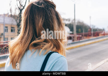 Die Rückseite des Kopfes einer jungen Frau auf der Straße. Close-up beeilen, Mädchen mit Zerzausten gewelltes Haar. Stockfoto