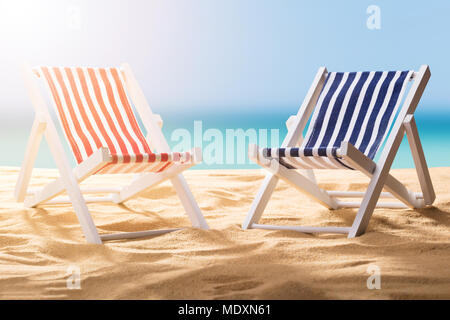 In der Nähe von zwei blau und rot gestreiften Liegestühle am Sandstrand Stockfoto