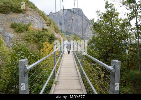 Eine Frau wandern entlang einer Brücke auf der Swiss Wine Trail in den Ausläufern der Berner Alpen, in der Nähe von Leytron, im Kanton Wallis, Schweiz. Stockfoto