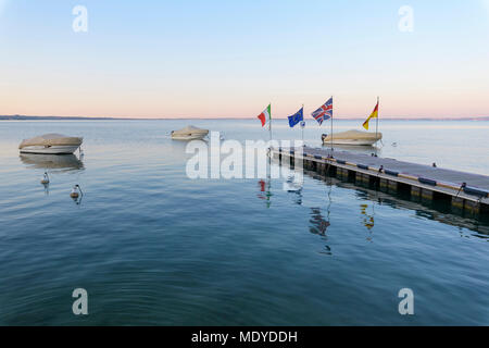 Bedeckt, Motorboote, das am Steg in der Morgendämmerung am Gardasee (Lago di Garda) in Bardolino in Venetien, Italien Stockfoto