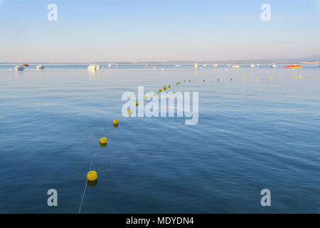 Gardasee (Lago di Garda) mit Line von Bojen und Boote in der Ferne in Bardolino in Venetien, Italien verankert Stockfoto