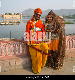 Ein Indisches Paar steht mit einem Grand Palace Posing, Jal Mahal, aus rotem Sandstein, im Mai Sagar See im Hintergrund versenkt Stockfoto