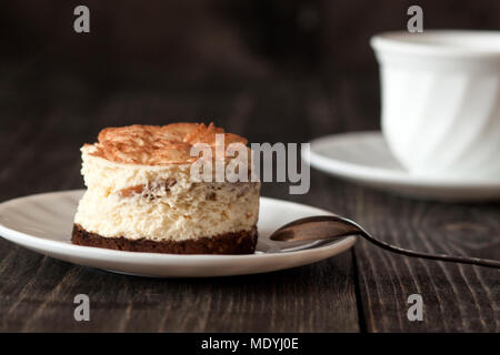 Tiramisu Kuchen auf einem weißen Teller und eine Tasse schwarzen Kaffee Stockfoto