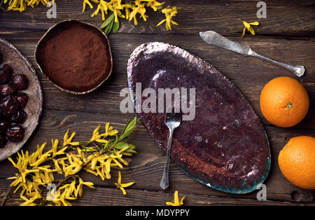 Flatlay leer essen Hintergrund mit leeren Teller, Orangen, Schokolade, gelbe Blumen, Messer und Gabel auf Holz, mit Platz für Text kopieren Stockfoto