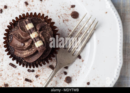 Chocolate Cupcake auf weißer Teller mit Gabel, bestäubt mit Kakao und Schokolade besprüht, Ansicht von oben Stockfoto