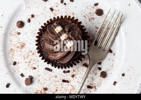 Chocolate Cupcake auf weißer Teller mit Gabel, bestäubt mit Kakao und Schokolade besprüht, Ansicht von oben Stockfoto