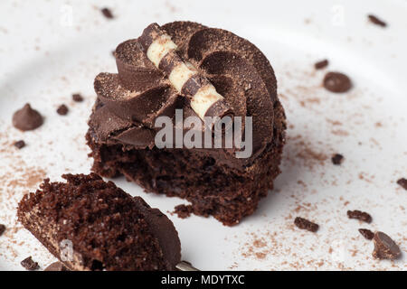 Chocolate Cupcake auf weißer Teller mit Gabel, bestäubt mit Kakao und Schokolade besprüht, die Hälfte gegessen Stockfoto