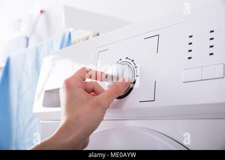 In der Nähe von Hand drehen einer Person" der Waschmaschine Stockfoto