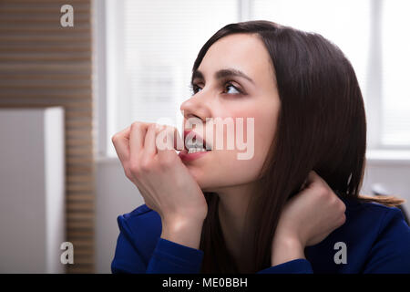 Portrait einer jungen betrachtet Geschäftsfrau beißen ihr Fingernagel Stockfoto