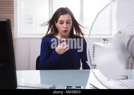 Junge Geschäftsfrau Sitzen auf Stuhl genießen Sie mit Elektrischer Ventilator Stockfoto