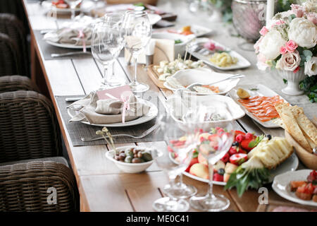 Girlande aus Blumen und Grün für die Tischdekoration. Luxus Hochzeit im Restaurant. Stilvolle Einrichtung und schmücken. Weiße Kerzen auf Glas candl Stockfoto