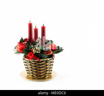 Drei brennende Rote Kerzen in Weihnachten thematisch dekorierten Weidenkorb isoliert auf weißem Stockfoto