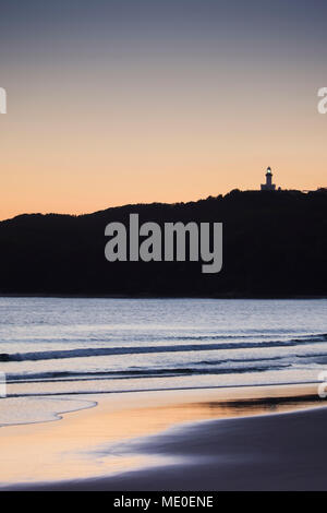 Silhouette von Cape Byron Lighthouse auf einem Hügel und am Strand bei Sonnenuntergang bei Byron Bay in New South Wales, Australien Stockfoto
