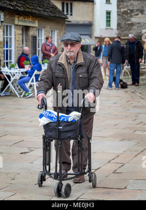 Älterer Mann mit einem drei-wheeld Rollator Spaziergänge durch Cirencester Stadtzentrum mit seinen Einkaufsmöglichkeiten in seinem Beutel Stockfoto