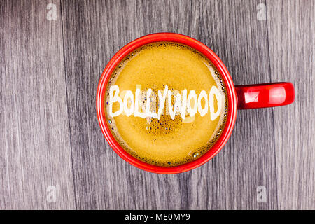 Konzeptionelle Hand schreiben Bollywood angezeigt. Business Foto Text das indische Kino eine Quelle der Unterhaltung Kaffee geschrieben in Rot Schale Grau Holz- backgroun Stockfoto